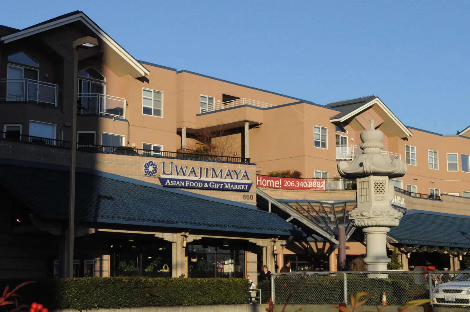 The Uwajimaya Asian food and gift market on Fifth Avenue South in Seattle, its blue awnings under apartments, with a stone lantern outside the entrance