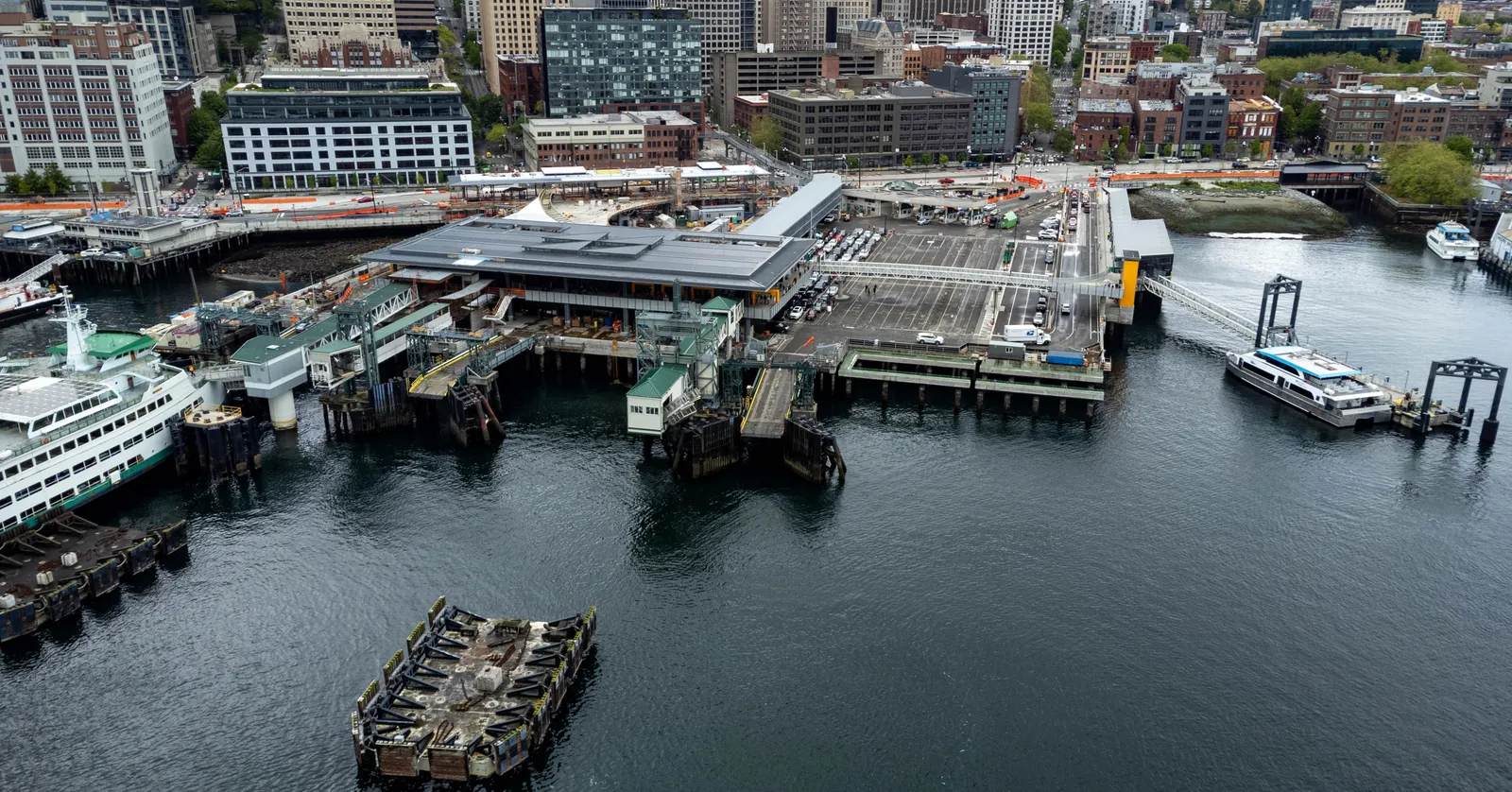 Colman Dock on Seattle's central waterfront seen from above, with its ferry slips, pilings and terminal building against the downtown blocks behind