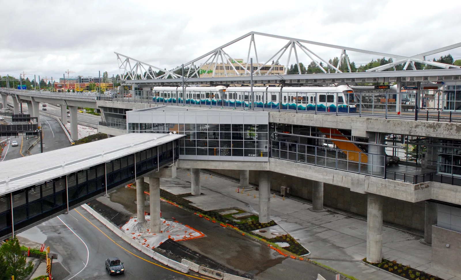 A light rail train at the elevated SeaTac/Airport station, seen from the airport parking garage with the covered walkway running toward the terminal