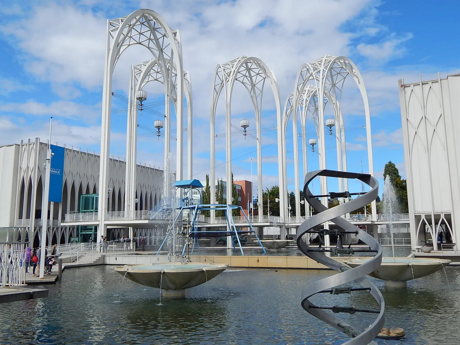 The five white lattice arches over the Pacific Science Center's courtyard pools in Seattle, with a spiral sculpture in the water below them