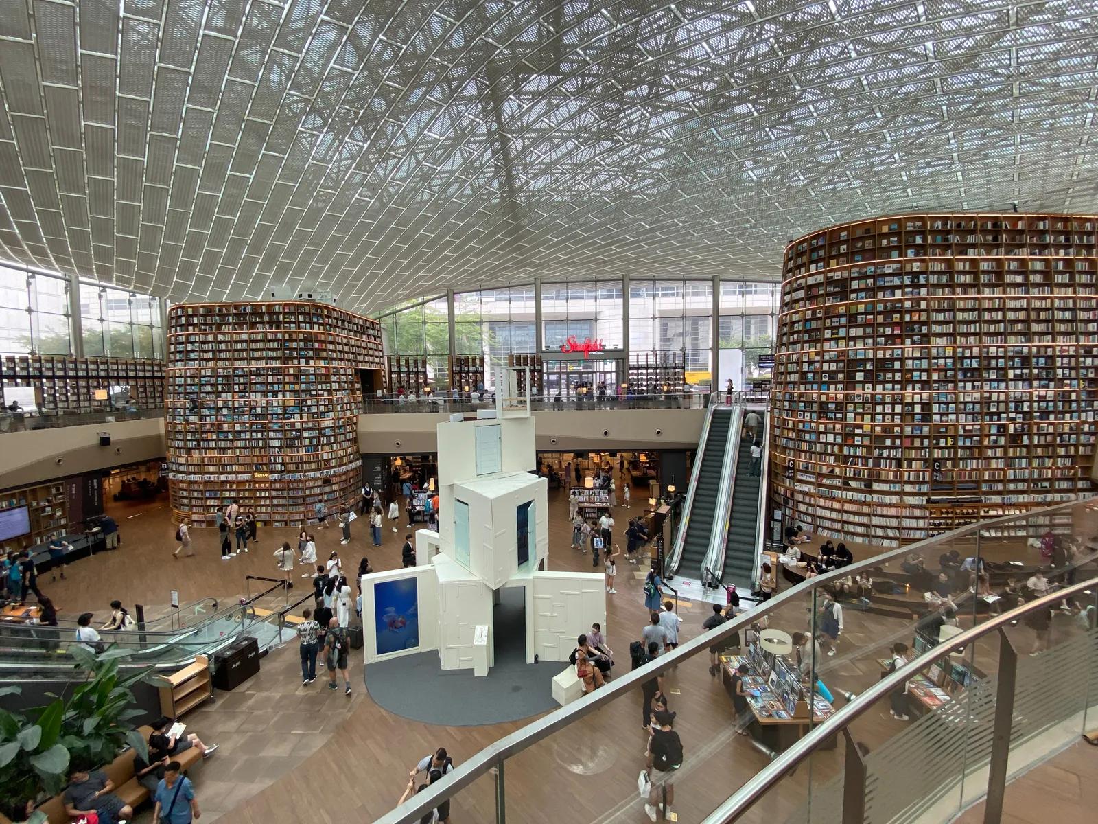 Starfield Library in COEX Mall, Seoul, a huge atrium under a lattice glass roof with curved walls of floor-to-ceiling bookshelves and escalators between the levels