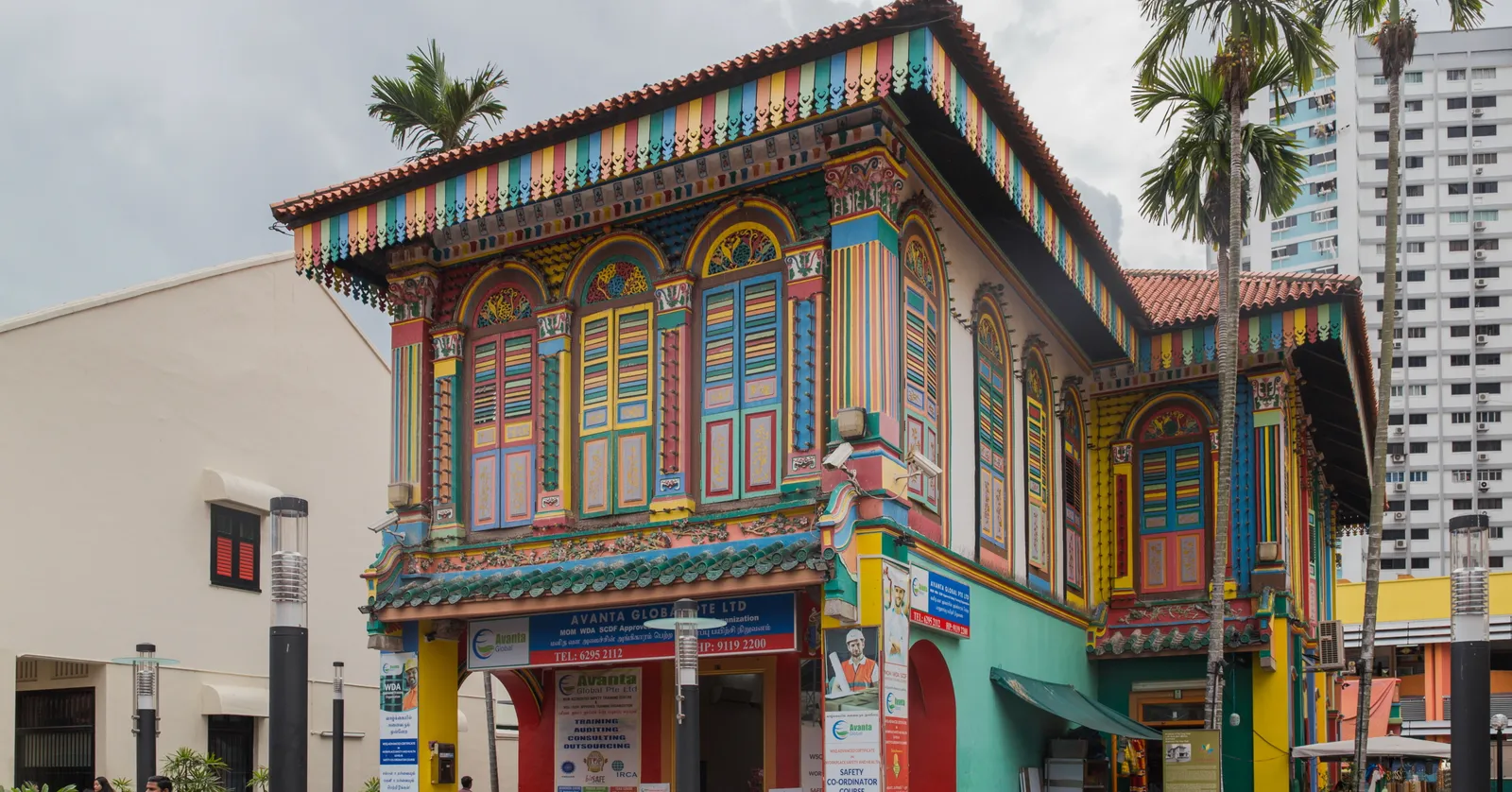 The House of Tan Teng Niah on Kerbau Road in Singapore, a two-storey villa with Chinese eaves painted in bands of green, yellow, blue, red and purple, palm trees and a modern block behind it