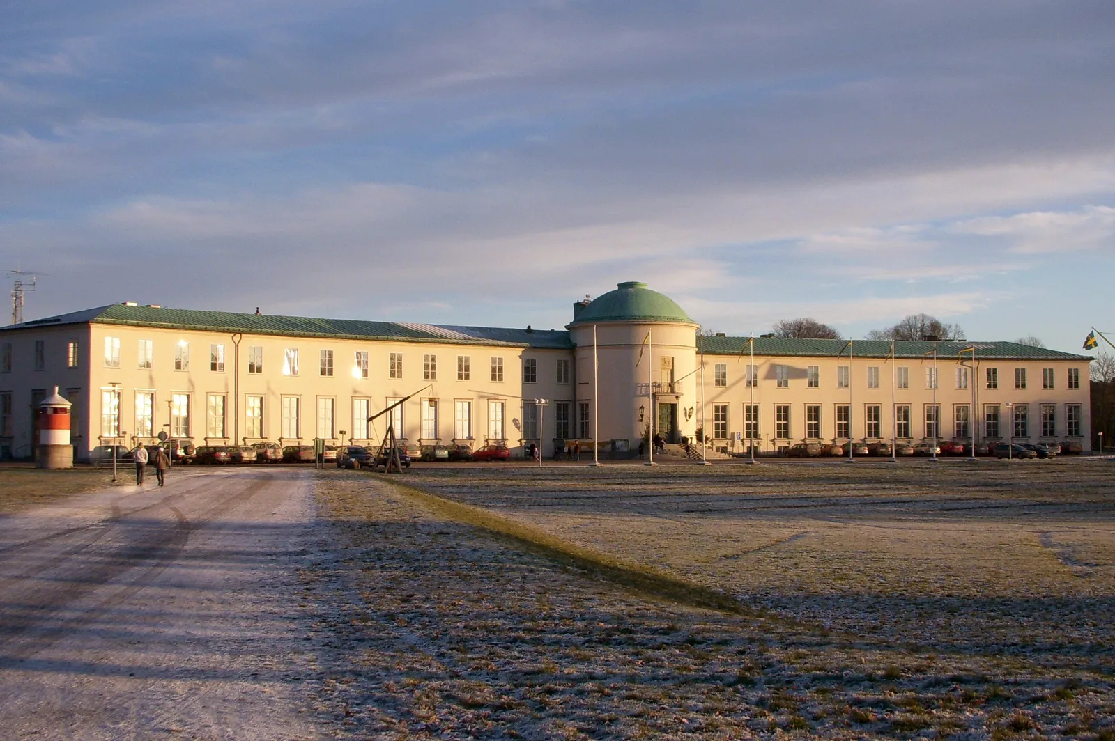 The Maritime Museum in Stockholm in low winter light, a long low pale building with a green copper dome over its centre, standing at the far edge of a wide frosted open field