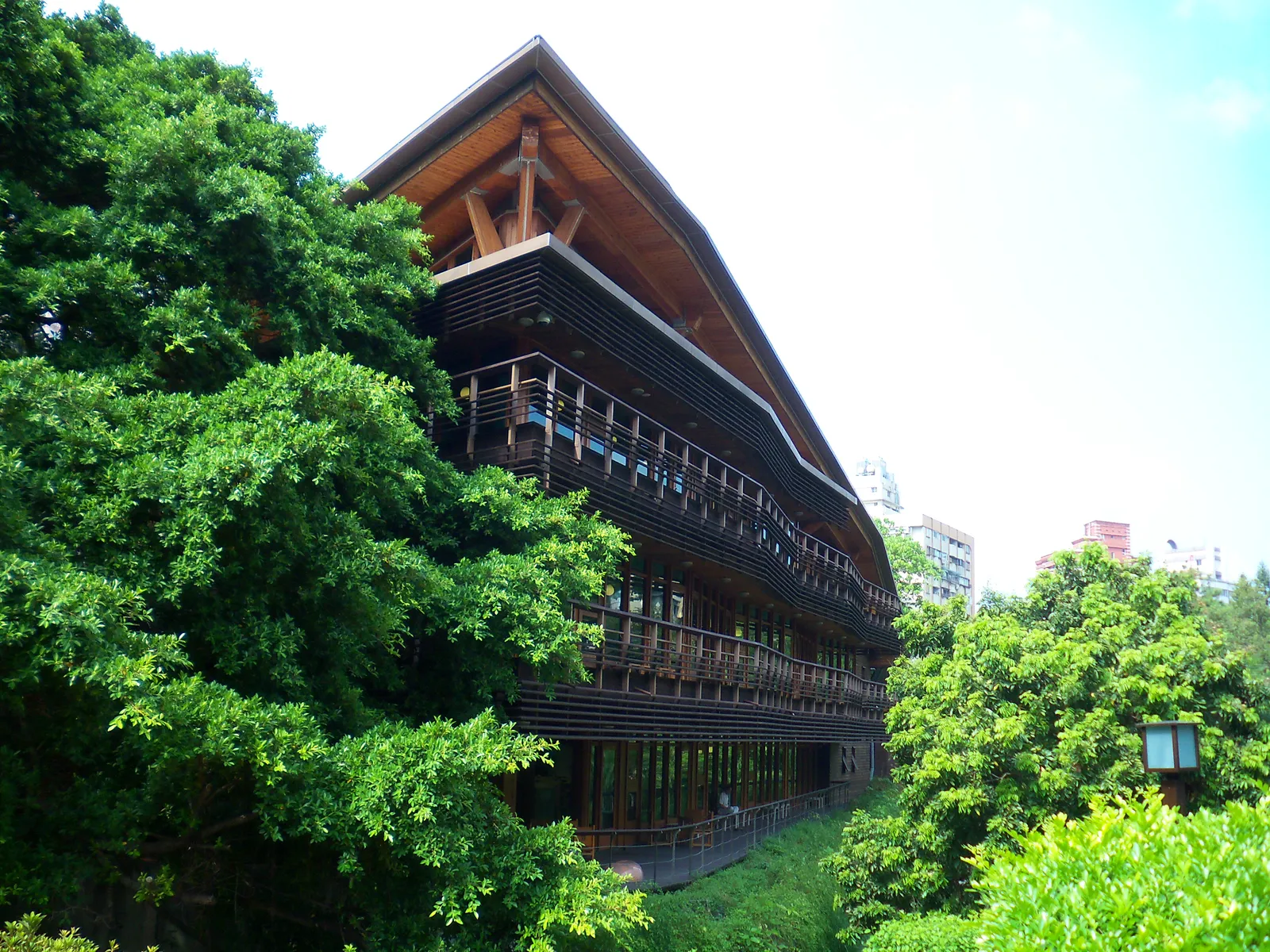 The timber-clad Beitou branch of the Taipei Public Library, a low building with deep balconies and a wide overhanging roof, surrounded by trees in Beitou Park