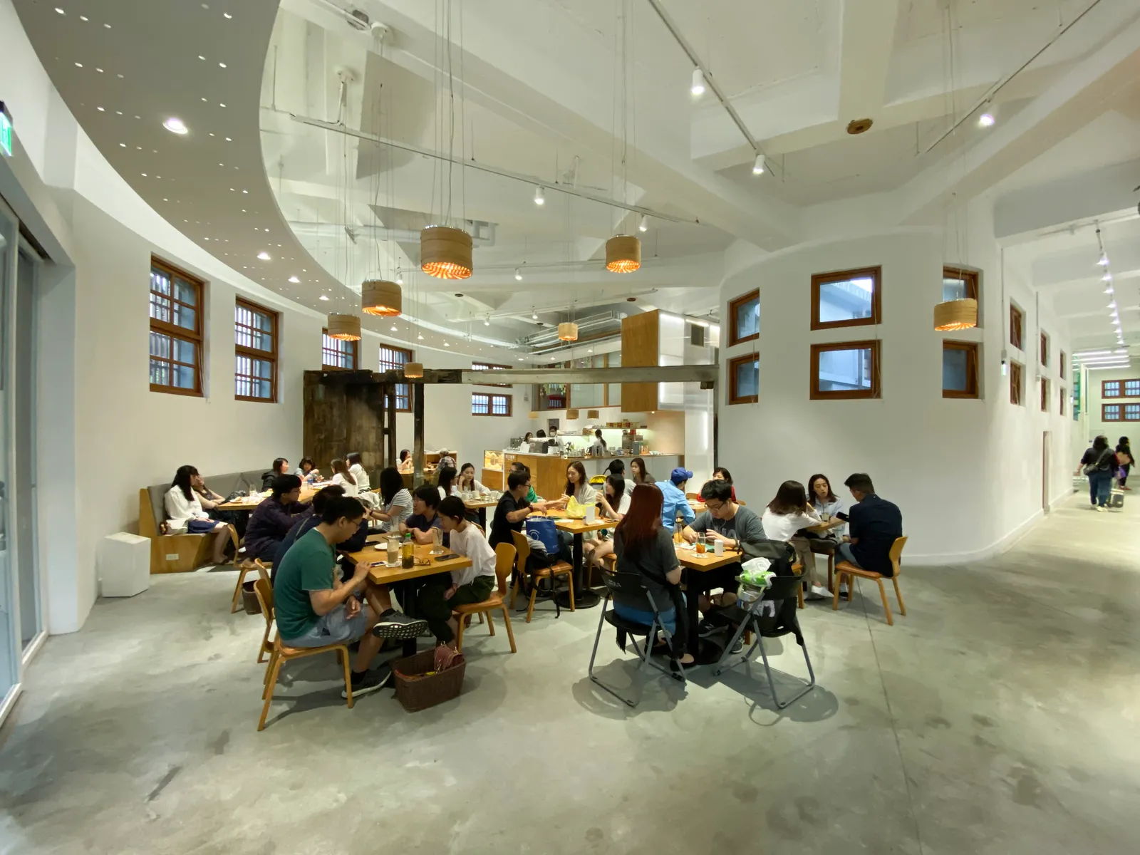 The curved white interior of the restored Xinfu Market in Taipei, a horseshoe-shaped 1930s hall with people eating at wooden tables under a ring-shaped ceiling