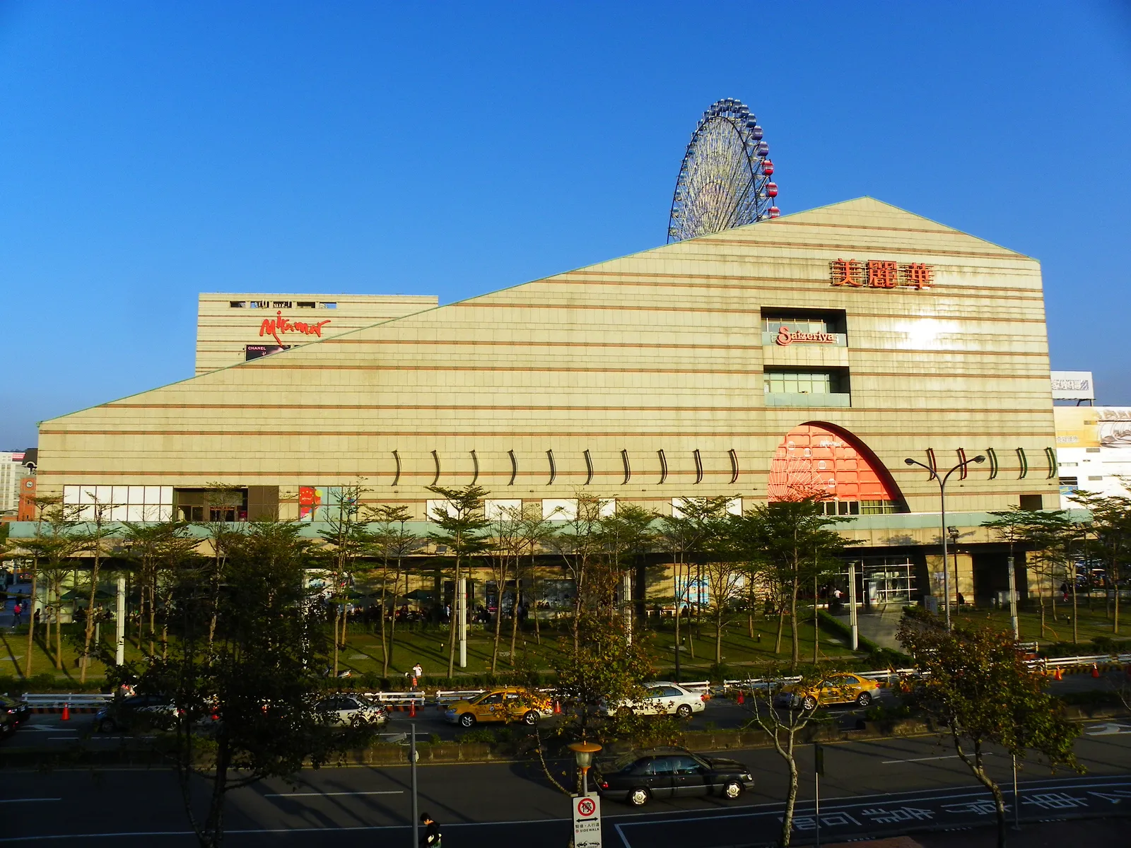 The Miramar Entertainment Park mall in Taipei's Dazhi district, a wide sand-coloured building with a Ferris wheel standing on its roof against a clear blue sky