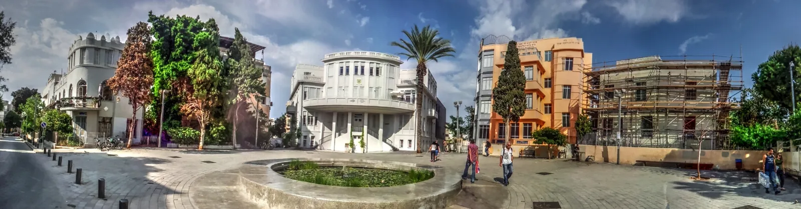 Bialik Square in Tel Aviv, the white curved front of the old city hall standing above a shallow round pond, with a tall palm beside it and an orange-rendered block closing the far side of the square