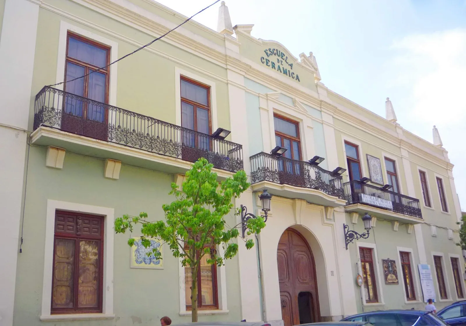 The old ceramics school building in Manises, a pale green and cream facade with iron balconies and the words Escuela de Cerámica lettered across the top