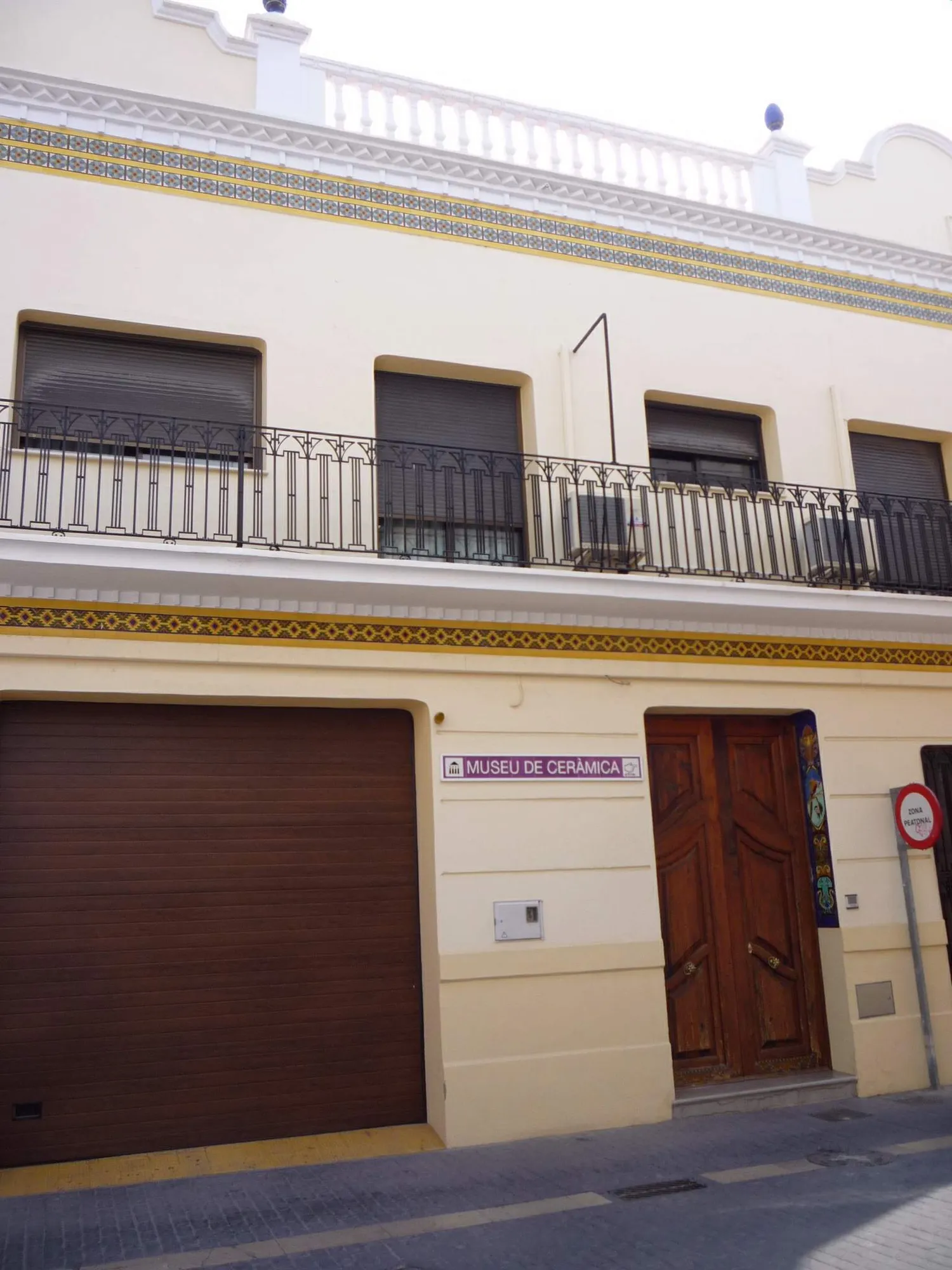 The street front of the ceramics museum in Manises, a cream townhouse with bands of blue and yellow tiles under the balcony and a sign reading Museu de Ceràmica above the door