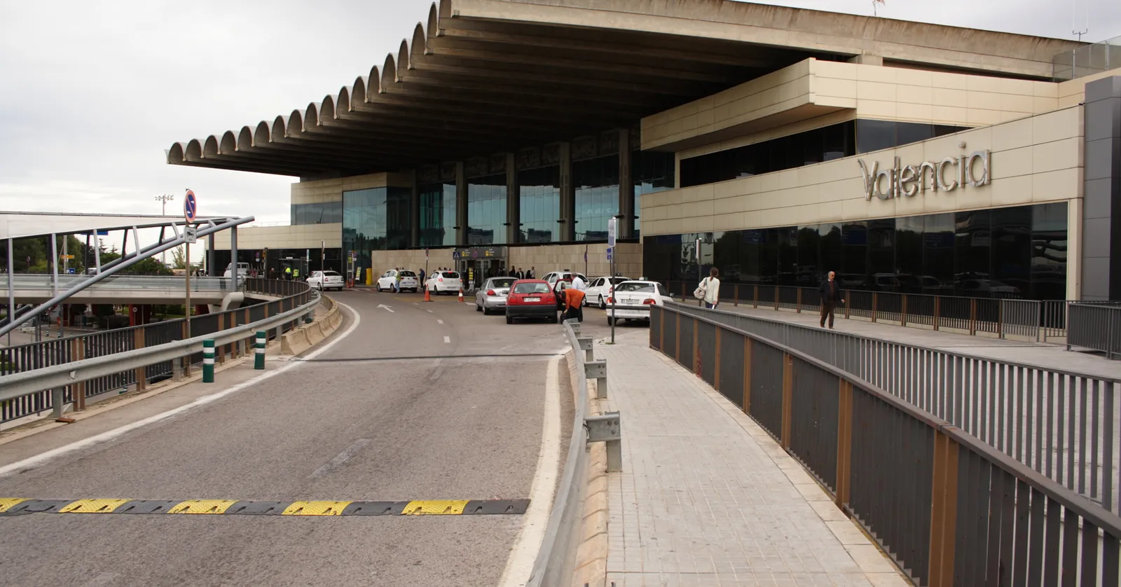 The front of the passenger terminal at Valencia Airport, a long concrete canopy over the departures road with the word Valencia lettered along the facade