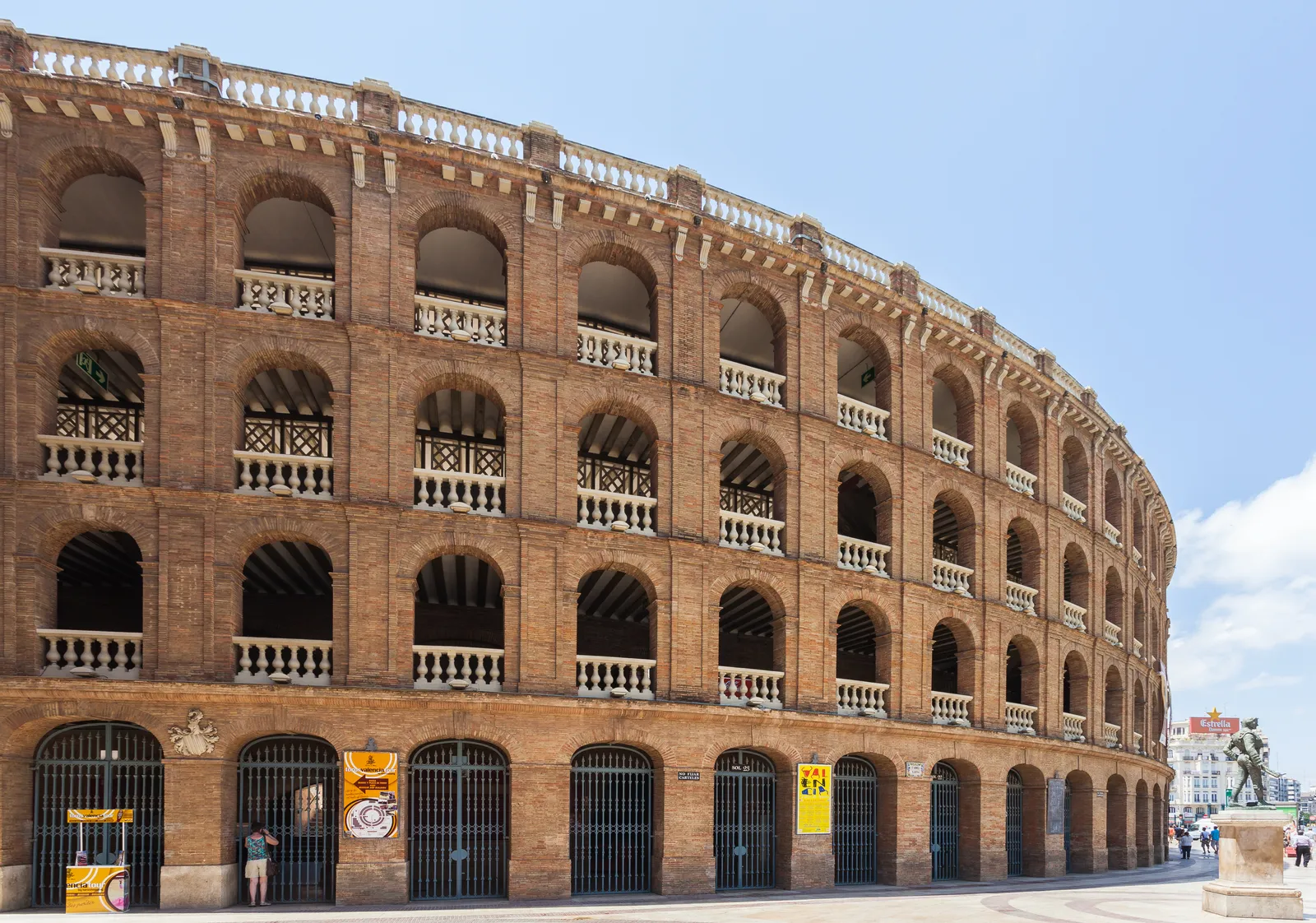 The curving brick exterior of the Valencia bullring, four tiers of open arches above street-level iron gates
