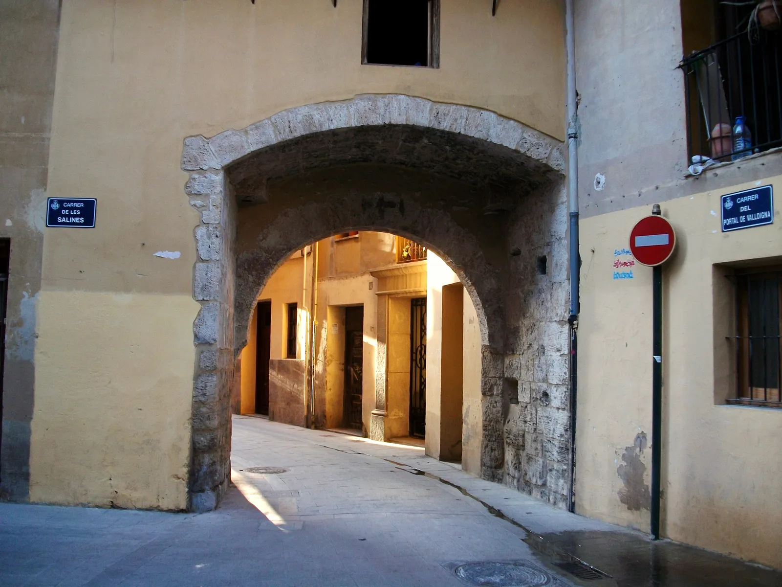 The Portal de la Valldigna in Valencia, a plain stone arch cut through a house front, with a narrow lane running away beyond it