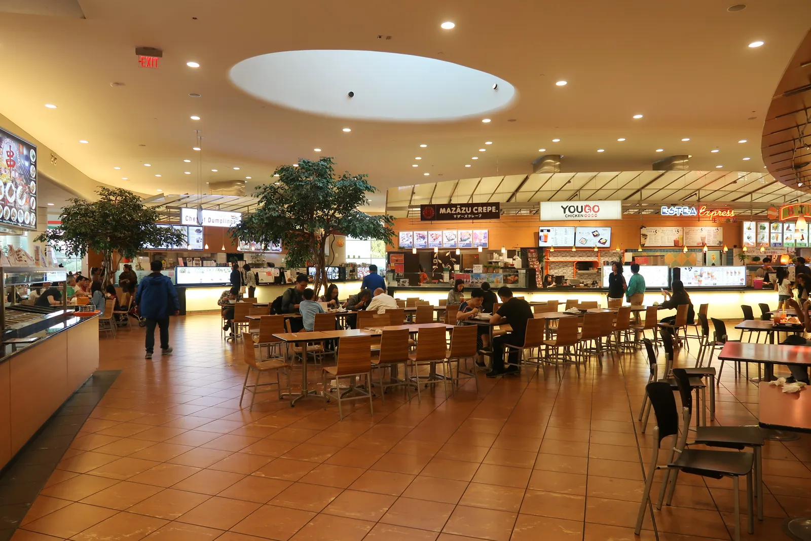 The 800-seat food court inside Aberdeen Centre in Richmond, BC, with diners at wooden tables under a skylight and a row of Asian food-counter storefronts behind