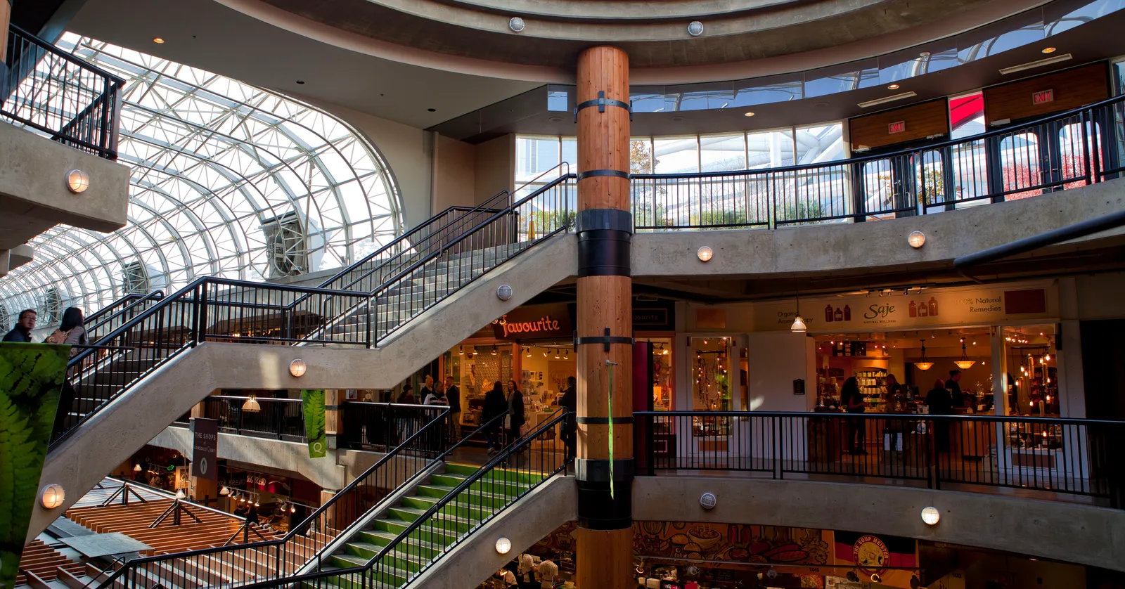 The multi-level atrium inside Lonsdale Quay Market in North Vancouver, a spiral staircase and a glass-domed skylight above shopfronts and a wood-clad support column