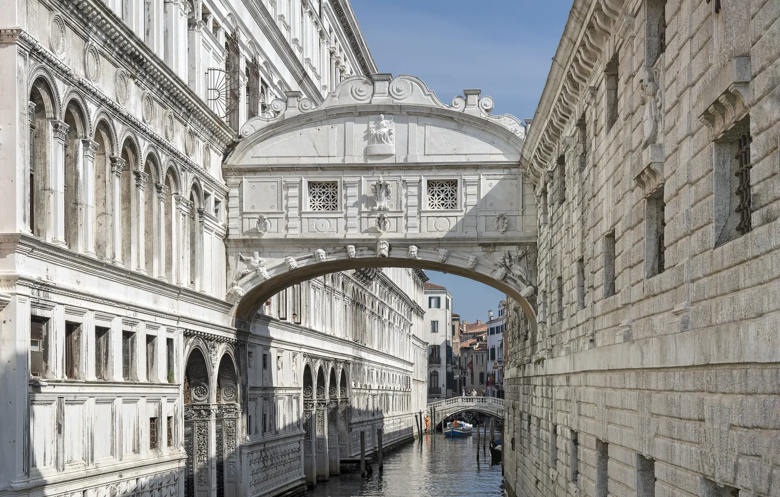 The enclosed white marble Bridge of Sighs arching between the Doge's Palace and the old prison building over a narrow Venice canal