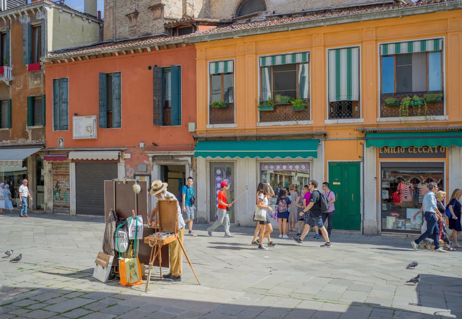Strada Nova in Venice's Cannaregio district lined with colorful buildings, shopfronts, and a street painter working outdoors