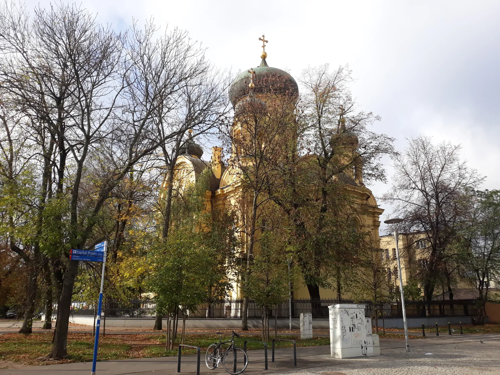The Orthodox Cathedral of St Mary Magdalene in Warsaw, a brick church in Russian Revival style with one large gilded onion dome and four smaller ones, seen through bare trees from the avenue