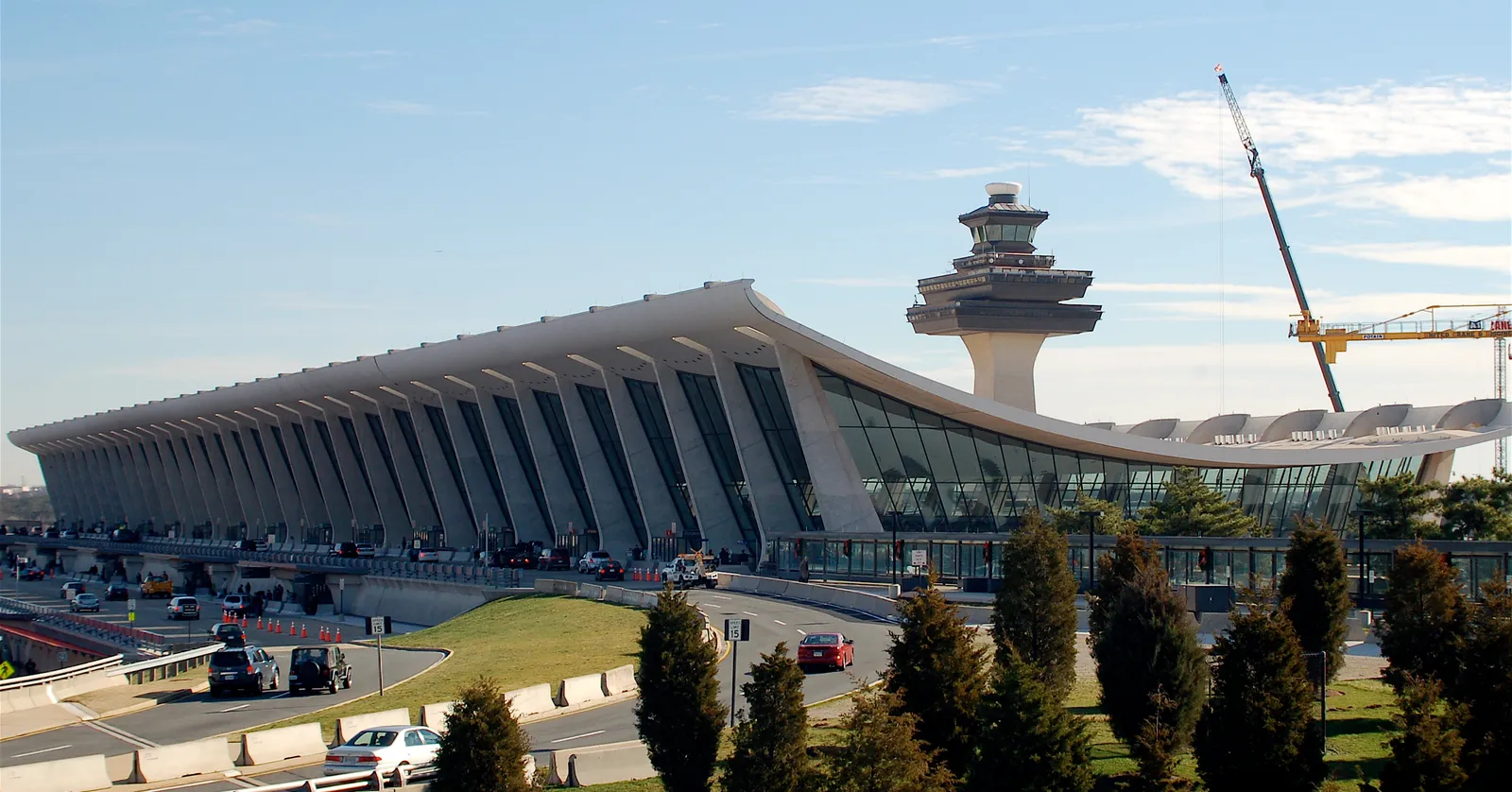 The main terminal at Washington Dulles International Airport, its concrete roof hanging in a long sagging curve between outward-leaning piers, with the flared control tower behind it