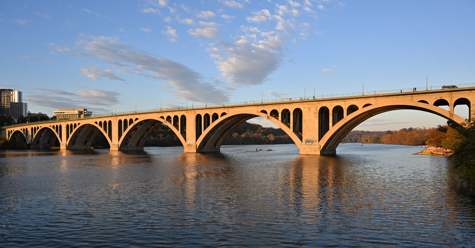 Key Bridge carrying its row of concrete arches across the Potomac beside the Georgetown waterfront in Washington, lit low by early sun