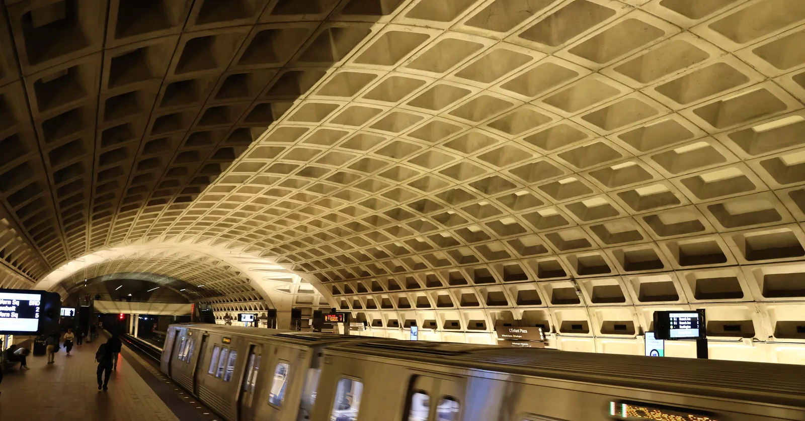 A platform at L'Enfant Plaza metro station in Washington under the coffered concrete vault typical of the system, with a train standing at the edge