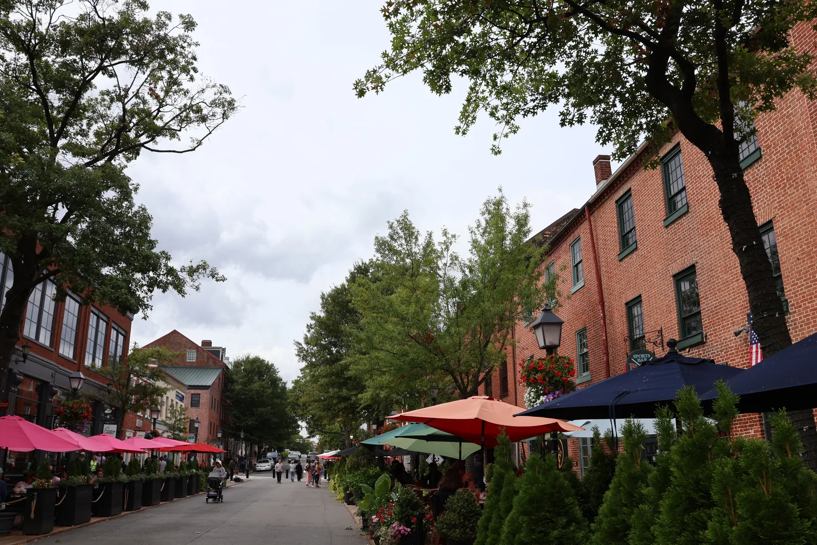 King Street in Old Town Alexandria, Virginia, lined with brick townhouses, awnings and café umbrellas under street trees