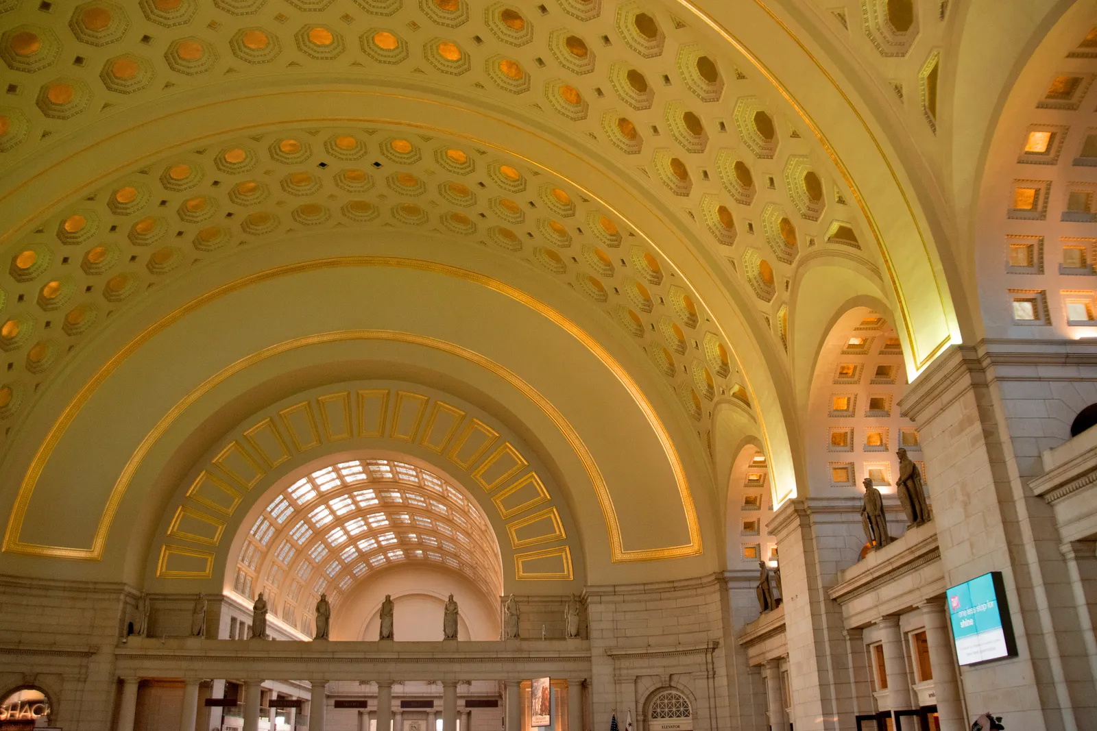 The barrel-vaulted ceiling of the Main Hall at Washington Union Station, its coffers picked out in gold leaf, with statues standing along the balcony ledge below